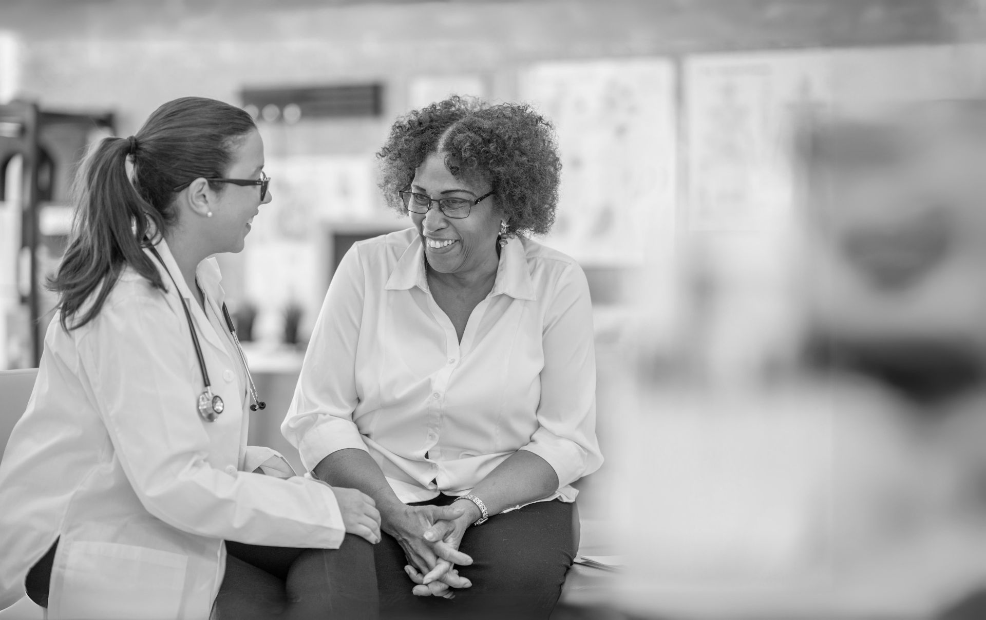 a female doctor speaks with a smiling female patient